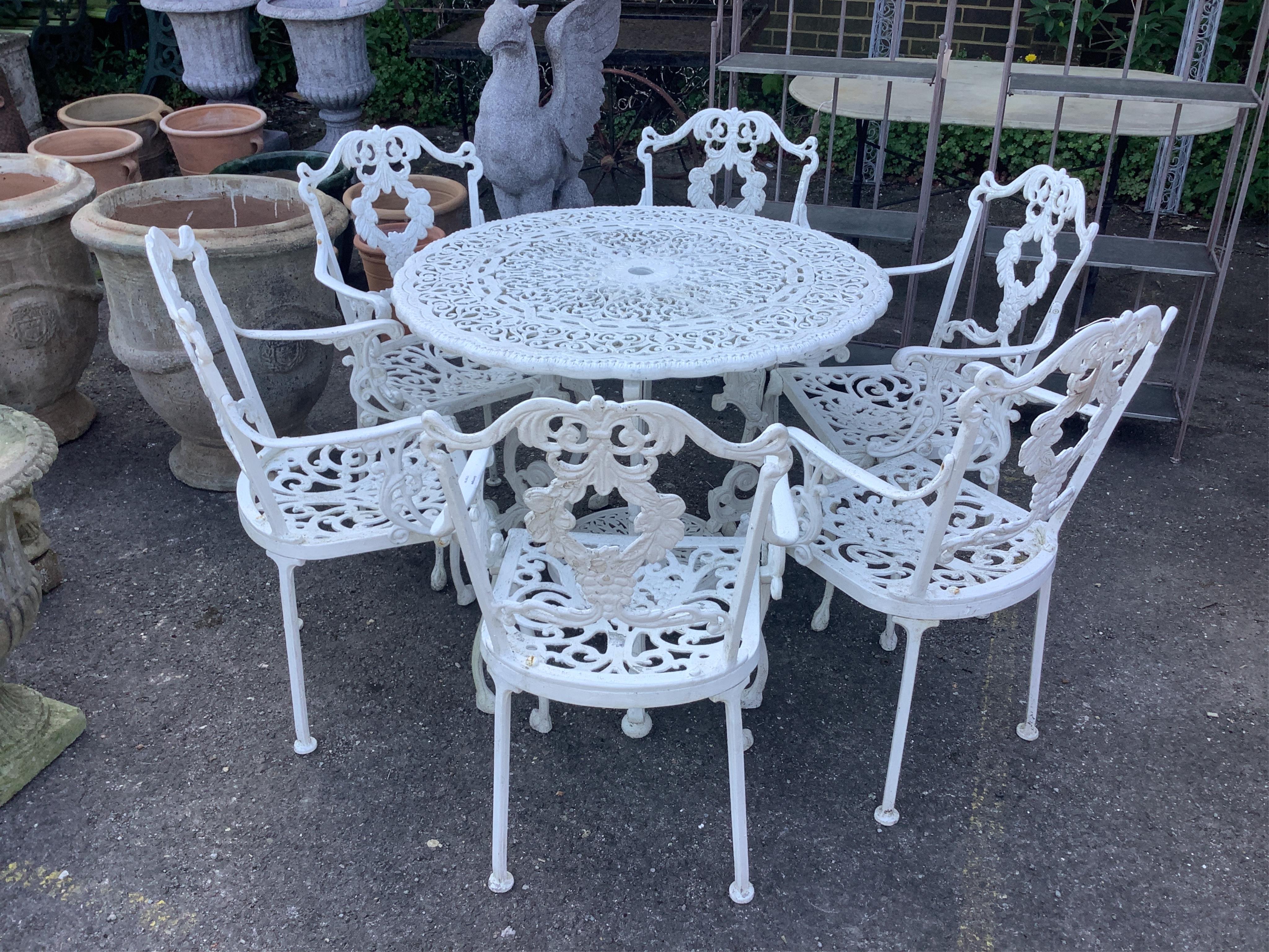 A Victorian style white painted circular aluminium garden table, diameter 90cm, height 72cm and six matching elbow chairs